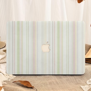 May include: A laptop case with a vertical striped pattern in pastel colors of white, pink, green, and gray. The Apple logo is visible in the center. The case is on a brown surface.