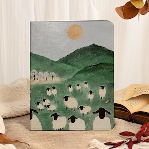 May include: A rectangular tablet case featuring a painted landscape of green rolling hills under a pale sky with a golden sun. The scene includes a flock of white sheep with black faces and legs grazing in a grassy field with small trees.