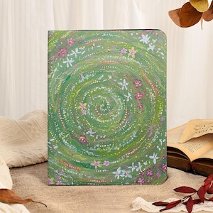 Puede incluir: Un diario verde con un diseño floral. La portada presenta un patrón en espiral con flores blancas, rosas y amarillas. El diario es rectangular y parece estar hecho de un material texturizado.