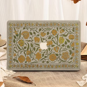 Könnte beinhalten: Eine Laptop-Hülle mit einem floralen Muster in Gelb-, Grün- und Beigetönen. Das Design zeigt stilisierte Blumen und Blätter, die von einem dekorativen Rahmen umschlossen sind. Das Apple-Logo ist sichtbar.