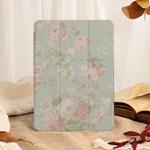 May include: A tablet case with a floral design. The case features a light green background with a pattern of pink and cream-colored flowers and green leaves. The case is rectangular and has a folding cover.