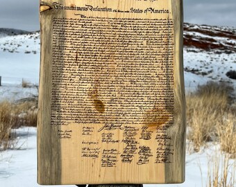 May include: A wooden sign with the text "In Congress, July 4, 1776. The unanimous Declaration of the thirteen united States of America." and the full text of the Declaration of Independence, including the signatures of the signatories.