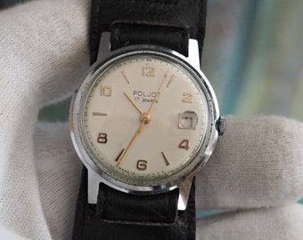 Puede incluir: Un reloj de pulsera plateado con una esfera blanca y una correa de cuero negra. La esfera del reloj tiene marcadores de hora romanos negros y agujas doradas. La esfera del reloj también tiene el texto "POLJOT 17 jewels".