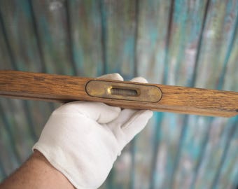 May include: A wooden level with a brass bubble level. The level is brown and has a natural wood finish.