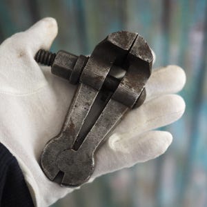 Puede incluir: Un tornillo de banco de mano vintage de metal con acabado plateado. El tornillo de banco está abierto y listo para sujetar.