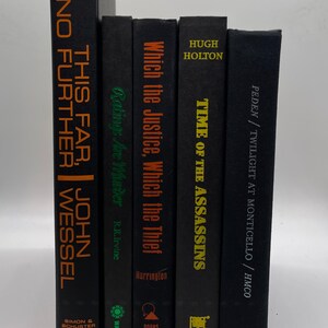 May include: A collection of five hardcover books with black covers. The titles and author names are printed in various colors, including orange, green, and gold. The books are arranged vertically, with the spines facing forward.