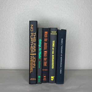 May include: A collection of hardcover books with dark covers and titles in gold and white. The titles include "This Far, No Further", "Ratings Are Murder", and "Time of the Assassins". The books are arranged vertically.