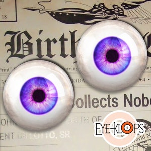 May include: Two purple and white eyeball-shaped craft supplies with black pupils. The eyeballs are on a vintage newspaper background with the word "Birth" printed in large letters.