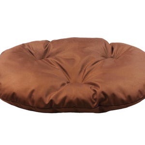 May include: A brown oval-shaped cushion with a tufted design. The cushion is made of a soft, plush fabric.