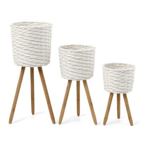 May include: Three white woven plant pots with wooden tripod legs. The pots are different sizes, creating a tiered display. The white color and natural wood tones offer a neutral aesthetic, suitable for various decor styles.