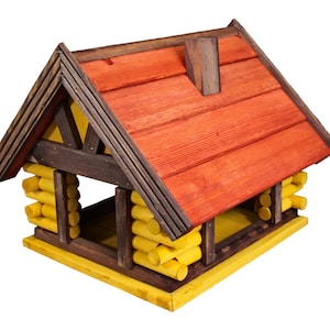 Peut inclure: Une mangeoire à oiseaux en bois en forme de petite maison avec un toit rouge et un bardage en rondins jaunes. La mangeoire a une grande ouverture à l'avant pour que les oiseaux puissent accéder à la nourriture.