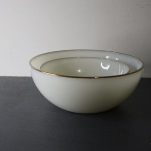 May include: Two white mixing bowls with a gold rim. The smaller bowl is nested inside the larger bowl.