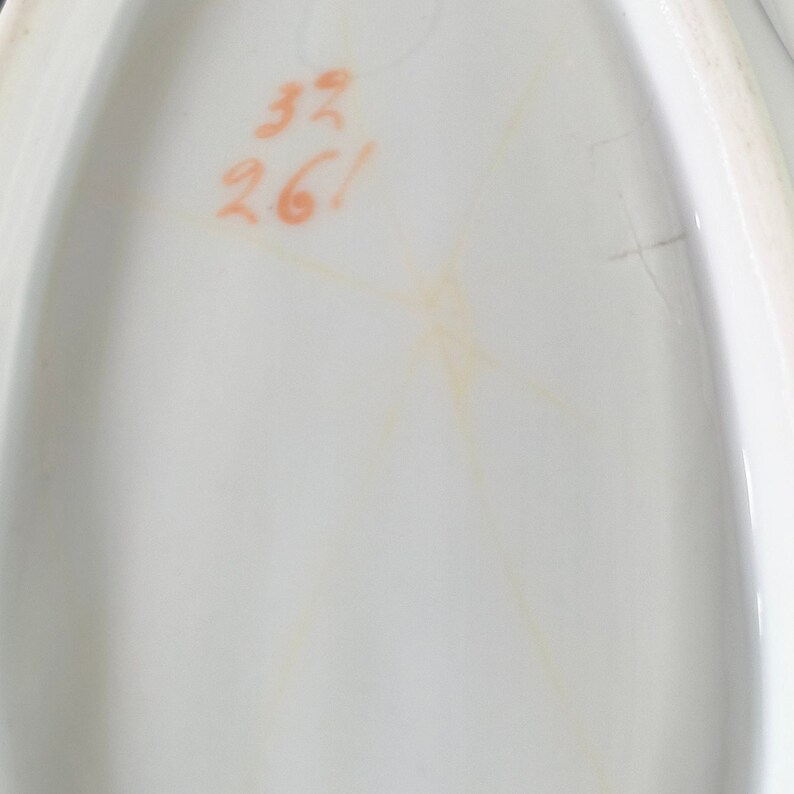May include: Close-up of a white oval ceramic dish with a handwritten inscription in orange ink that reads "33 26!"