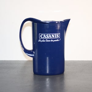 Peut inclure: Un pichet en plastique bleu avec un logo blanc qui dit "CASANIS Le plus Casa des pastis!"