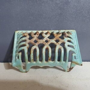 Pu&ograve; includere: Una griglia in ghisa blu chiaro con un design decorativo. La griglia &egrave; progettata per adattarsi all'apertura di un camino.