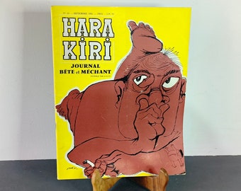 May include: A vintage magazine cover featuring a yellow background with the title "Hara Kiri" in black and white text. The magazine is labeled "Journal Bete et Mechant" in smaller text. The cover features a cartoon illustration of a person with a red body and a white face, lying on their side with their hand on their chin.