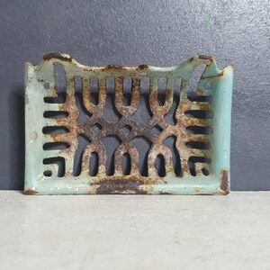 Pu&ograve; includere: Un portasapone vintage in ghisa con un design decorativo traforato. Il portasapone &egrave; dipinto di blu chiaro e ha un aspetto rustico e invecchiato.