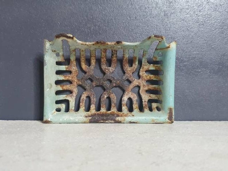 Pu&ograve; includere: Un portasapone vintage in ghisa con un design decorativo traforato. Il portasapone &egrave; dipinto di blu chiaro e ha un aspetto rustico e invecchiato.