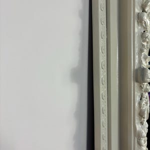 Pu&ograve; includere: Una cornice per foto bianca ornata con un bordo decorativo. La cornice &egrave; in legno e ha una finitura anticata.