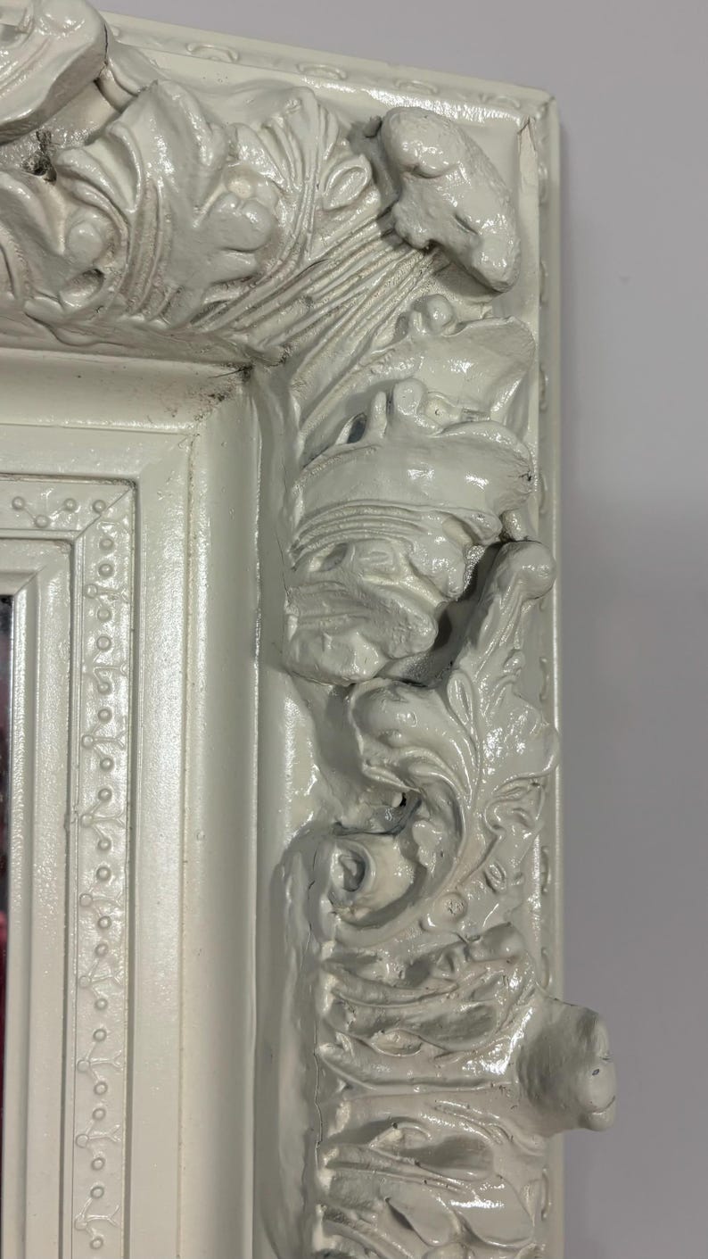 Pu&ograve; includere: Una cornice per specchio bianca ornata con intagli intricati e un bordo perlato. La cornice &egrave; in legno e ha una finitura anticata.