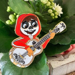 May include: A white ceramic mug with a black handle and the text "But First, Coffee" in a bold, black font. The mug is set against a blurred background, suggesting a cosy setting.