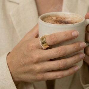 May include: A set of three ceramic mugs with a speckled, matte finish. Each mug features a different color: light blue, cream, and gray. The mugs have a simple, modern design, perfect for coffee or tea.