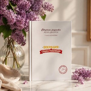 Puede incluir: Un libro de tapa dura blanca con el título "Сборник рецепти РЕТРО ДЕСЕРТИ Гинка КЕХАЙОВА" y "ОПЕРАЦИЯ СЛАДКА РЕВОЛЮЦИЯ" impreso en la portada. El libro presenta un sello rojo circular en la esquina inferior derecha y un diseño limpio.