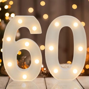 May include: A pair of large, white, three-dimensional number signs representing 60, each featuring integrated warm white LED lights embedded within the structure to create a glowing effect across the surface of the numbers.