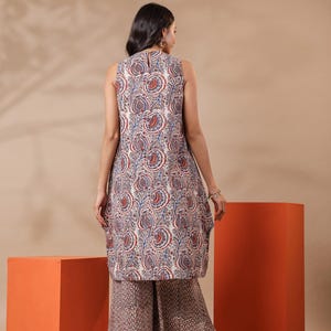 May include: A sleeveless tunic and wide-leg pants set. The tunic features a white base with a paisley pattern in red and blue. The pants have a complementary brown and white geometric print. The outfit is suitable for casual wear.
