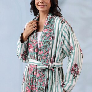 May include: A floral print robe with a striped pattern in shades of white, teal, and pink. The robe has a matching belt and a floral design on the collar and cuffs. The robe is made of a soft, lightweight fabric.
