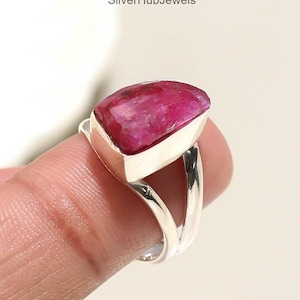 Könnte beinhalten: Ein silberner Ring mit einem großen, leuchtend rosa Edelstein. Der Edelstein hat eine einzigartige, unregelmäßige Form und ist in einem polierten Silberband gefasst. Das Design des Rings ist modern und auffällig, perfekt, um jedem Outfit einen Farbtupfer zu verleihen. Es ist ein Schmuckstück.