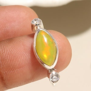 May include: A silver ring with a yellow opal gemstone and two small clear cubic zirconia stones.