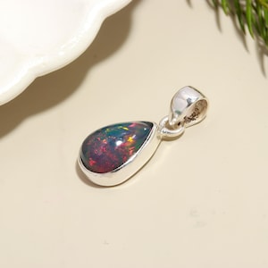 May include: A teardrop-shaped pendant with a black opal gemstone set in sterling silver.