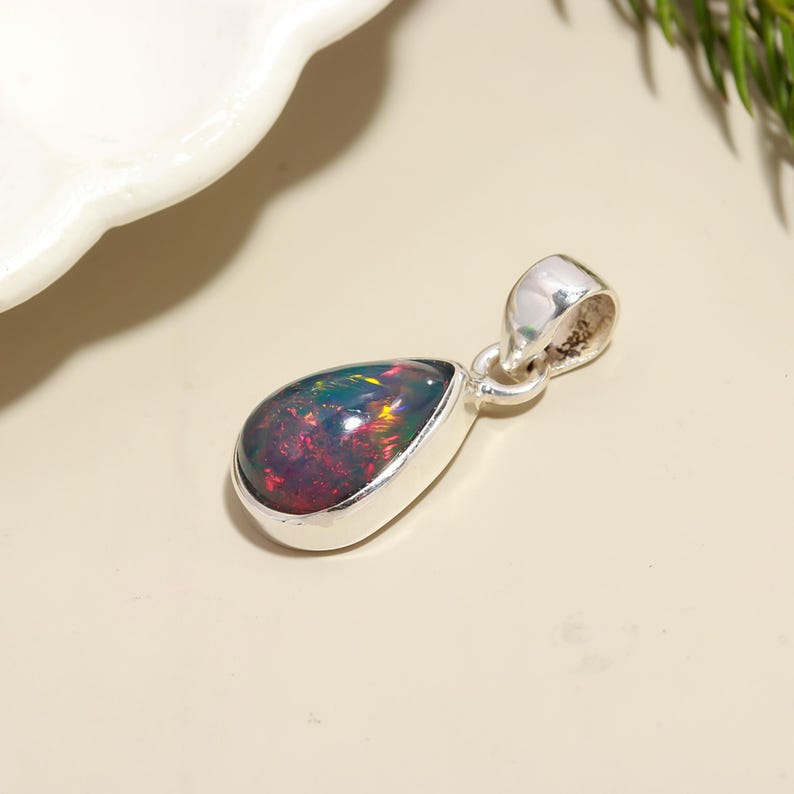 May include: A teardrop-shaped pendant with a black opal gemstone set in sterling silver.