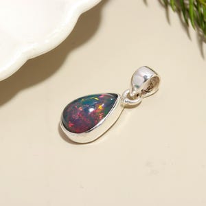 May include: A teardrop-shaped pendant with a black opal gemstone set in sterling silver.