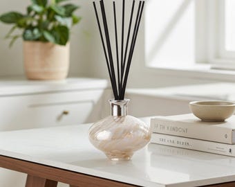 Difusor de varetas em vidro soprado, formato oval, com design em azul brilhante e branco.