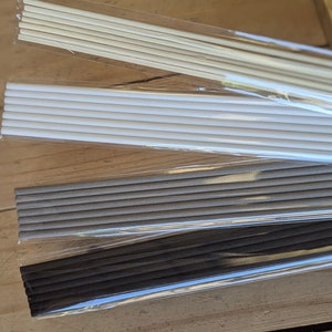 May include: Four sets of diffuser reeds in different colours and sizes. The reeds are packaged in clear plastic bags. The reeds are white, grey, and black.
