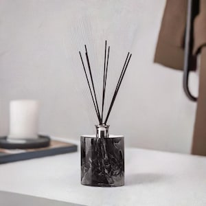 Könnte beinhalten: Schwarze und weiße Marmor-Diffuserflasche mit schwarzen Diffusorstäbchen.