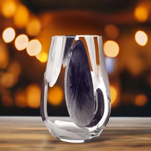 May include: A clear glass vase with a unique, wavy design. The vase is empty and has a dark, almost black, reflection inside.