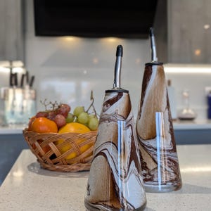 May include: Two brown and white marbled glass oil and vinegar bottles with silver spouts.