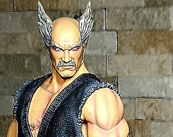 Puede incluir: Una figura de un hombre calvo con patillas blancas, que lleva un uniforme de karate negro con un cinturón rojo. Tiene una expresión seria en su rostro y está de pie sobre una base texturizada.