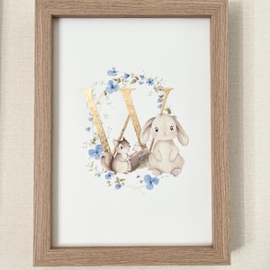 Può includere: Stampa incorniciata con la lettera dorata "X" circondata da fiori blu e verde. Uno scoiattolo e un coniglio sono posizionati sotto la lettera. L'opera d'arte è in una cornice di legno chiaro.