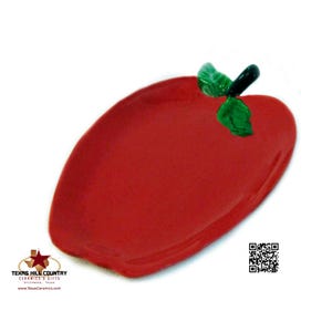 May include: A red ceramic apple shaped serving dish with a green leaf and stem.