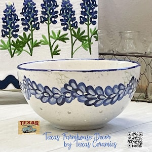 May include: A white ceramic bowl with a blue floral design and a blue rim. The bowl has small holes and is decorated with blue flowers. The text "Texas Farmhouse Decor by Texas Ceramics" is visible.
