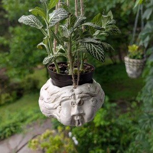 Vaso da fiori sospeso in ceramica vintage con volto stilizzato.