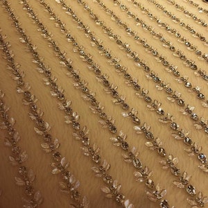 May include: A close-up of a white fabric with a repeating pattern of silver beads arranged in a leaf design. The fabric is 100% hand-made.