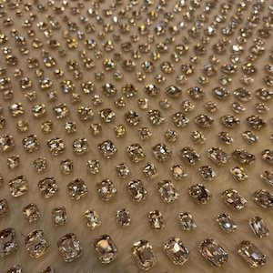 Puede incluir: Una tela blanca con un patrón de brillantes rectangulares transparentes. Los brillantes están dispuestos en un patrón repetitivo.