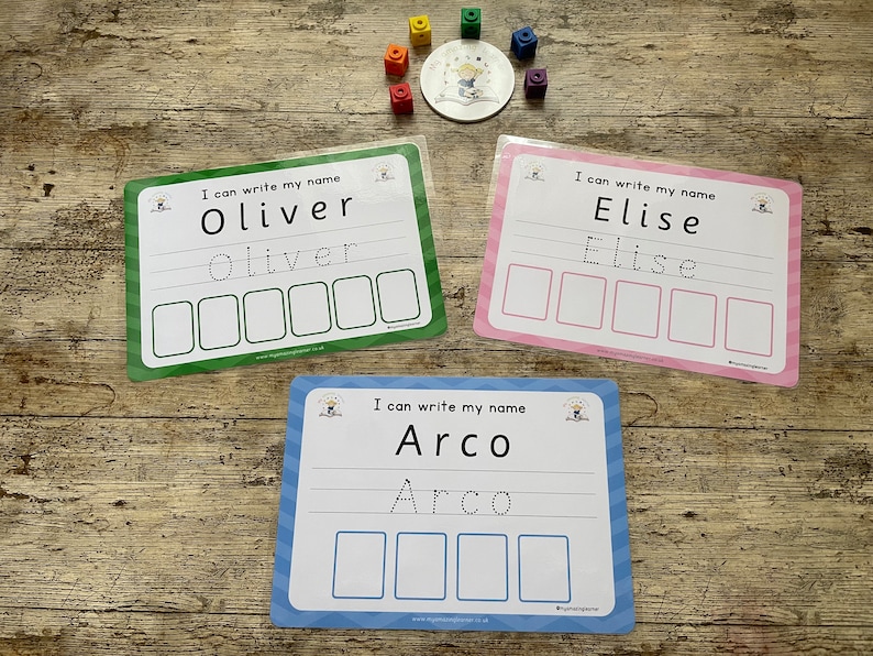 Pode incluir: Tr&ecirc;s cart&otilde;es laminados coloridos com uma linha pontilhada e espa&ccedil;os em branco para praticar a escrita de nomes. Os cart&otilde;es s&atilde;o verde, rosa e azul e apresentam os nomes "Oliver", "Elise" e "Arco".