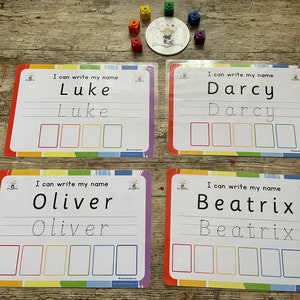 May include: Four colourful laminated cards with rainbow borders. Each card has a name printed at the top, followed by the same name written in dotted lines for tracing. Below the name are five blank boxes.