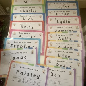 Pode incluir: Um conjunto de cart&otilde;es coloridos com a frase "Eu posso escrever meu nome" e um espa&ccedil;o para escrever um nome. Os nomes incluem Leon, Mia, Charlie, Nico, Betsy, Annika, Stephen, Isaac, Paisley, Alex, Ethan, Taylor, Kaden, Lydia, Summer, Aoife, Aiden, Edee, Reeva e Ben.